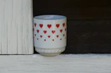 Close-up of a vibrant handmade ceramic mug with a heart-shaped handle on a wooden table.
