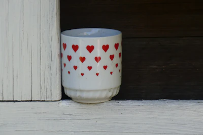 Close-up of a vibrant handmade ceramic mug with a heart-shaped handle on a wooden table.