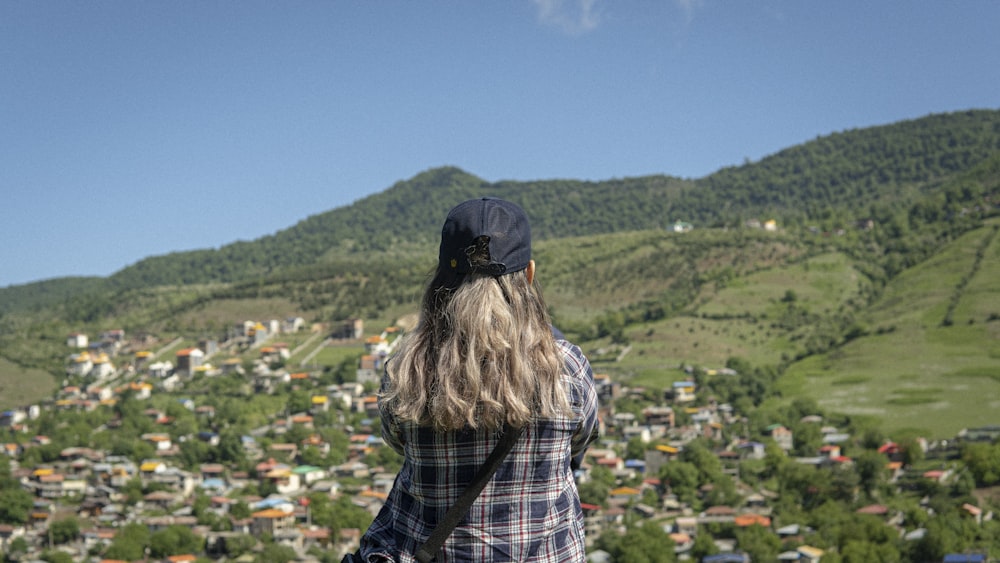 a woman standing on a hill looking at a town