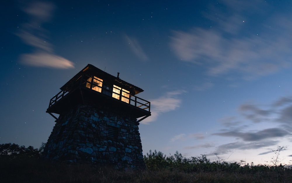 a small tower sitting on top of a hill under a night sky