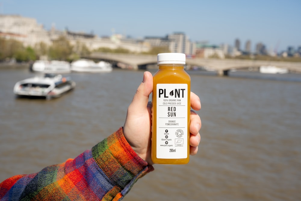 a person holding up a bottle of orange juice