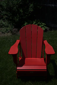 A sleek aluminum Adirondack chair set on a sunlit porch surrounded by greenery.