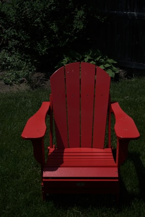 An aluminum Adirondack chair placed on a sunlit porch surrounded by greenery