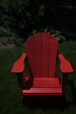 A sleek aluminum Adirondack chair set on a sunlit porch surrounded by greenery.