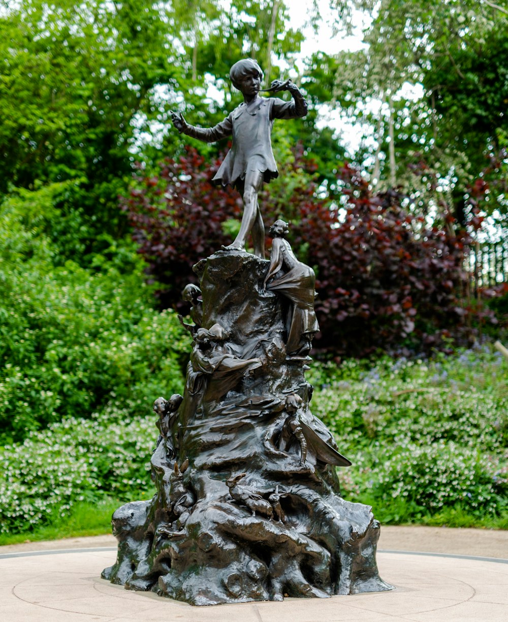 a statue of a boy on top of a rock