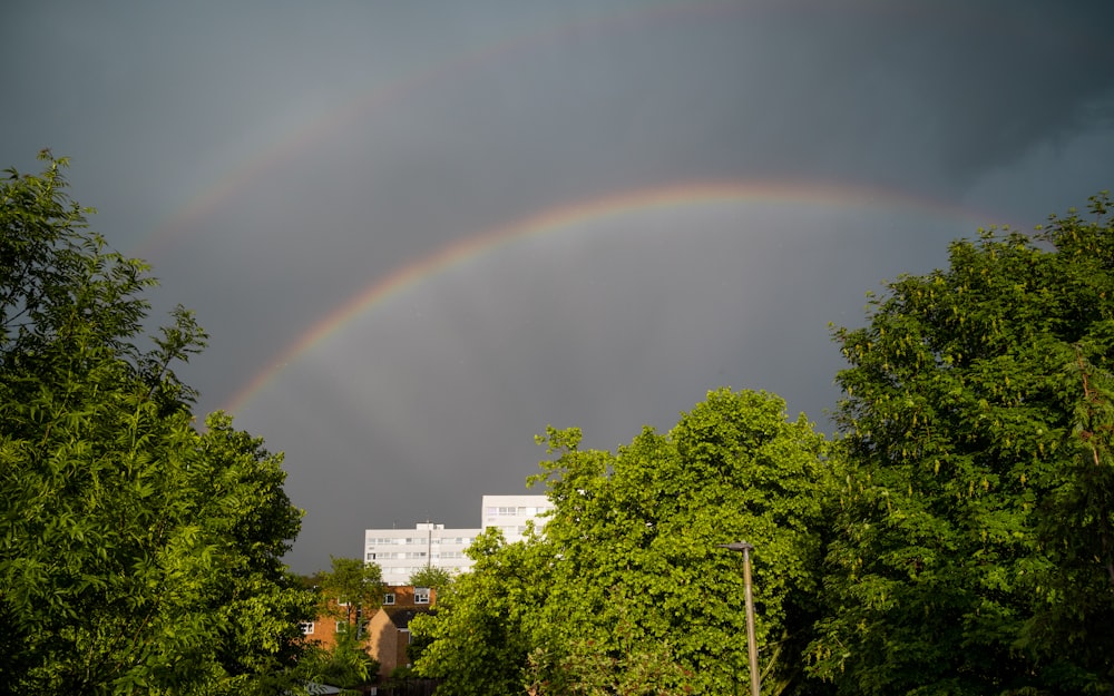 a double rainbow in the sky over some trees