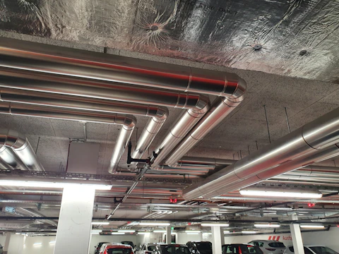 A modern multi-level parking garage with visible fire safety systems and ventilation ducts.