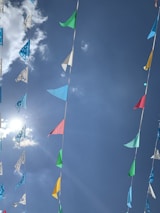 Colorful banners and flags fluttering outside a stadium under a clear blue sky.