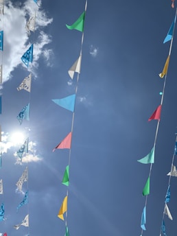Colorful banners and flags fluttering outside a stadium under a clear blue sky.