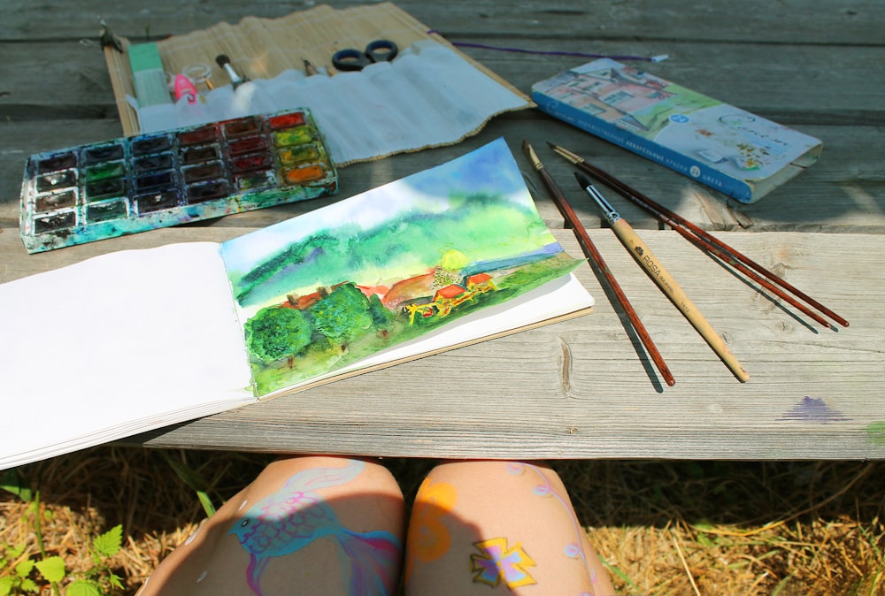 a person's feet with paint and a book on a table