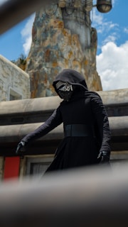 Illustration of a mysterious figure cloaked in gears and steam, standing atop a rooftop at dusk.