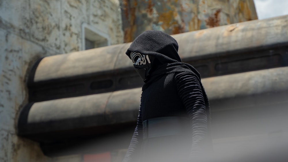 a person in a black hoodie is standing in front of a building