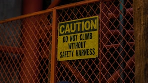 a yellow caution sign on a metal fence