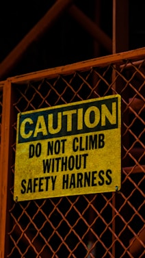 a yellow caution sign on a metal gate