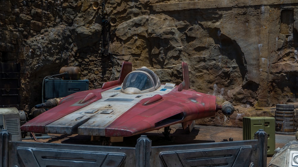 a red and white car parked in front of a rock wall