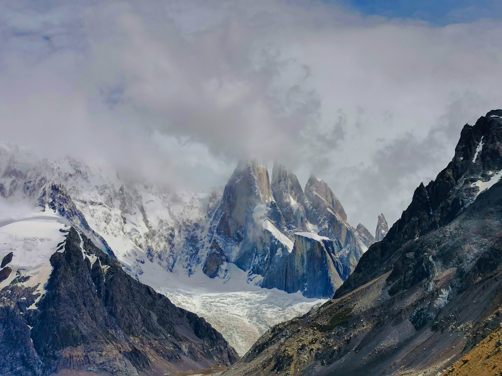 a mountain range covered in snow under a cloudy sky