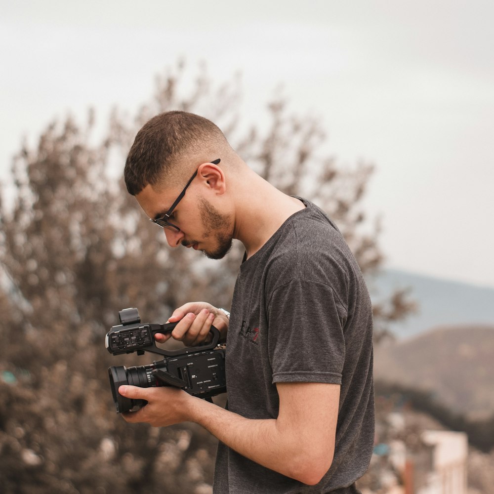 a man holding a camera and looking at it