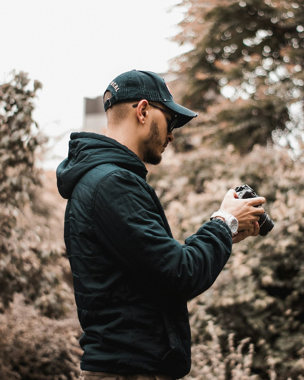 a man in a green jacket holding a camera