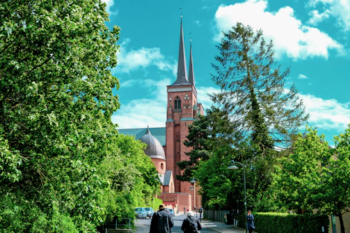 two people walking down a street in front of a church