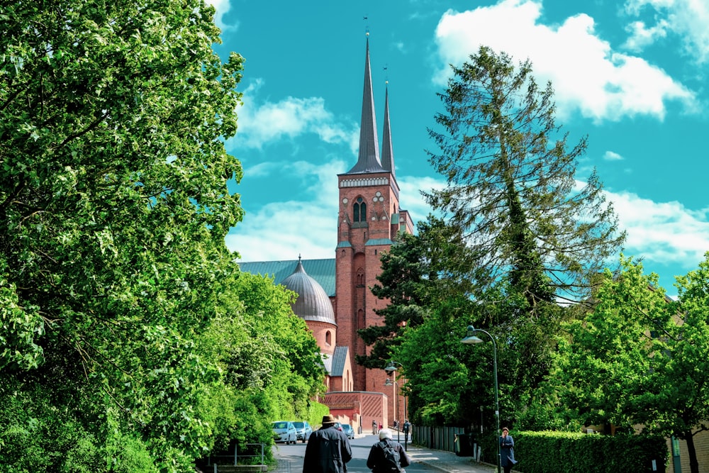 two people walking down a street in front of a church