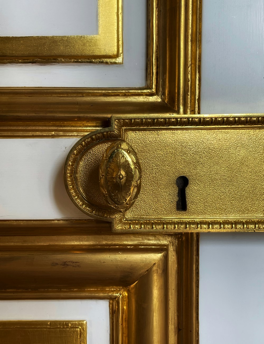 a golden door handle on a white and gold door