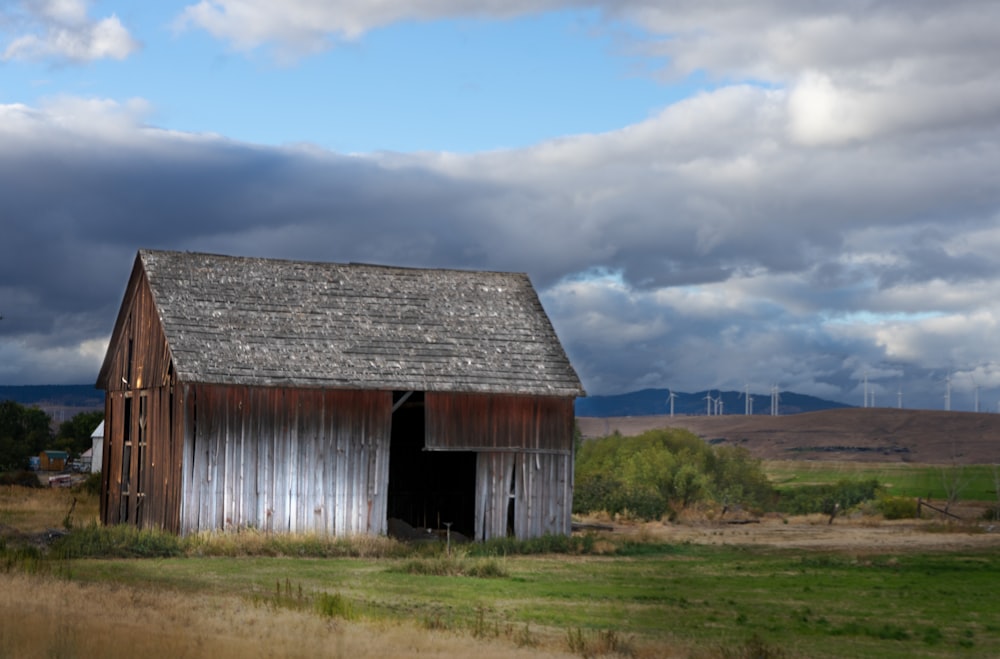 a barn in a field with a wind turbine in the background