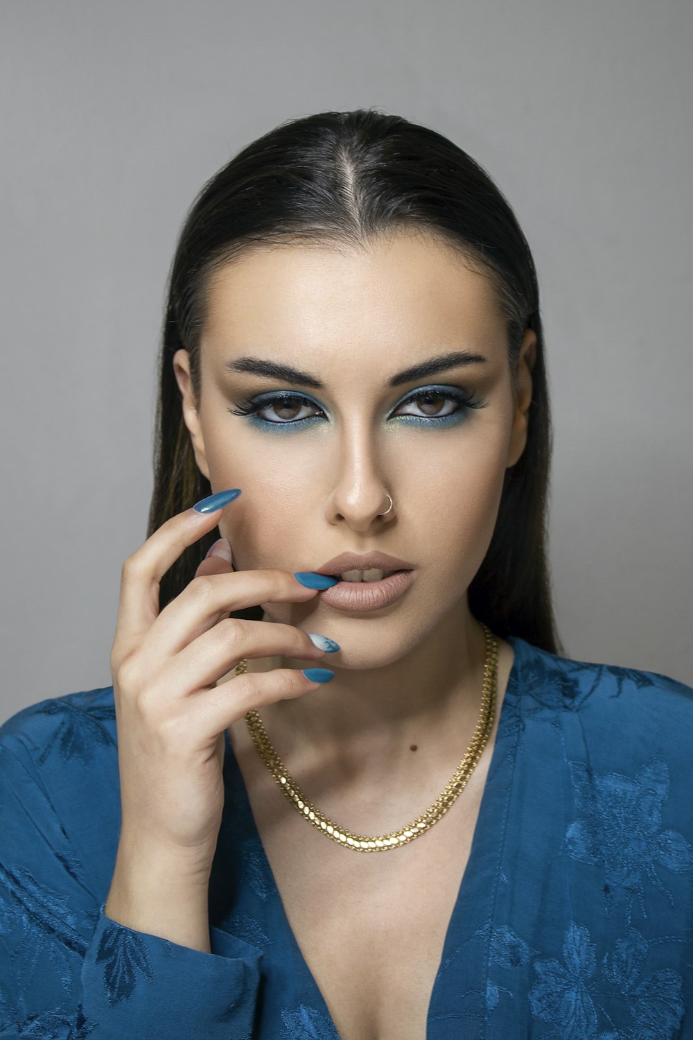 uma mulher com maquiagem azul segurando a mão em seu rosto