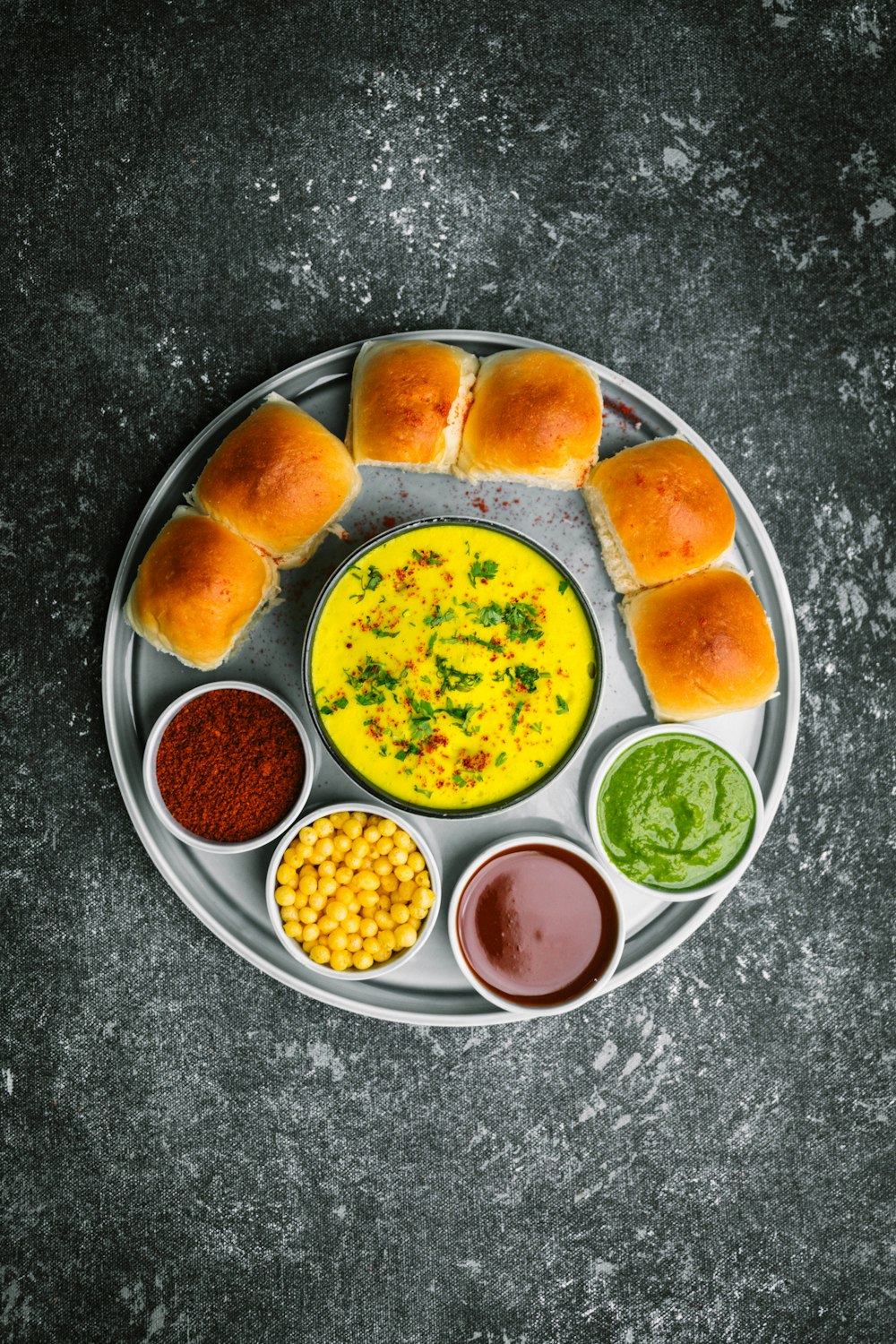 a plate of food that includes bread, dips, and sauces