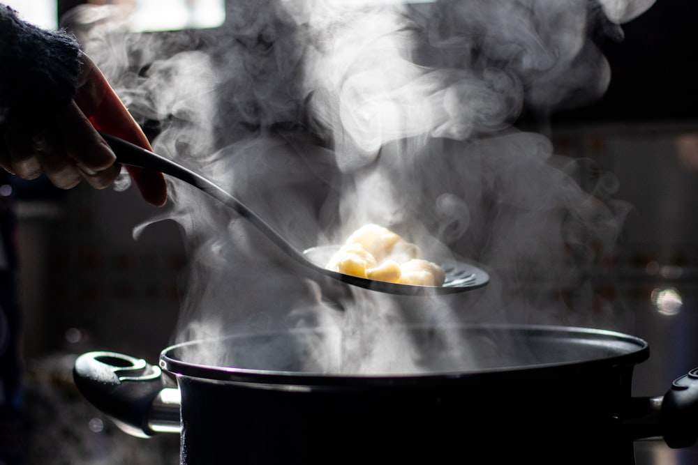 a person stirring food in a pot on a stove