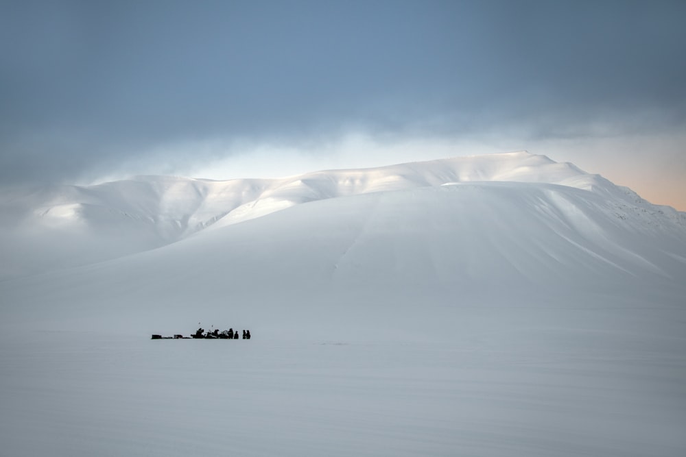 a group of people riding a snowmobile across a snow covered field