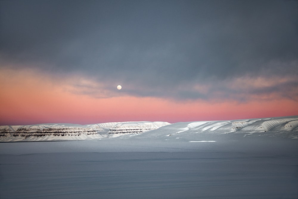 o sol está se pondo sobre uma paisagem nevada