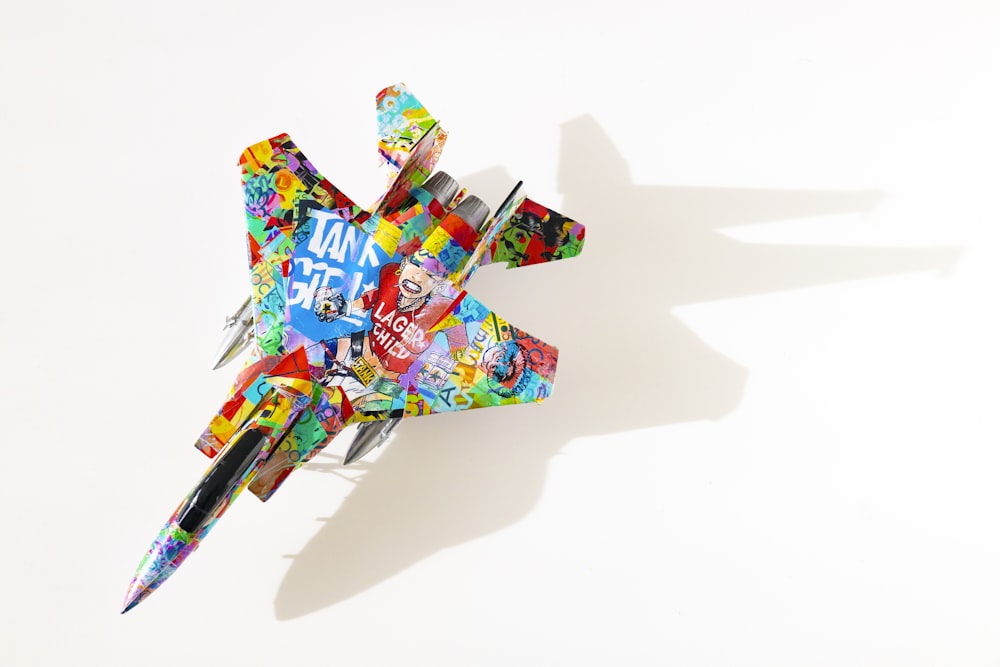 a multicolored toy airplane is flying in the air