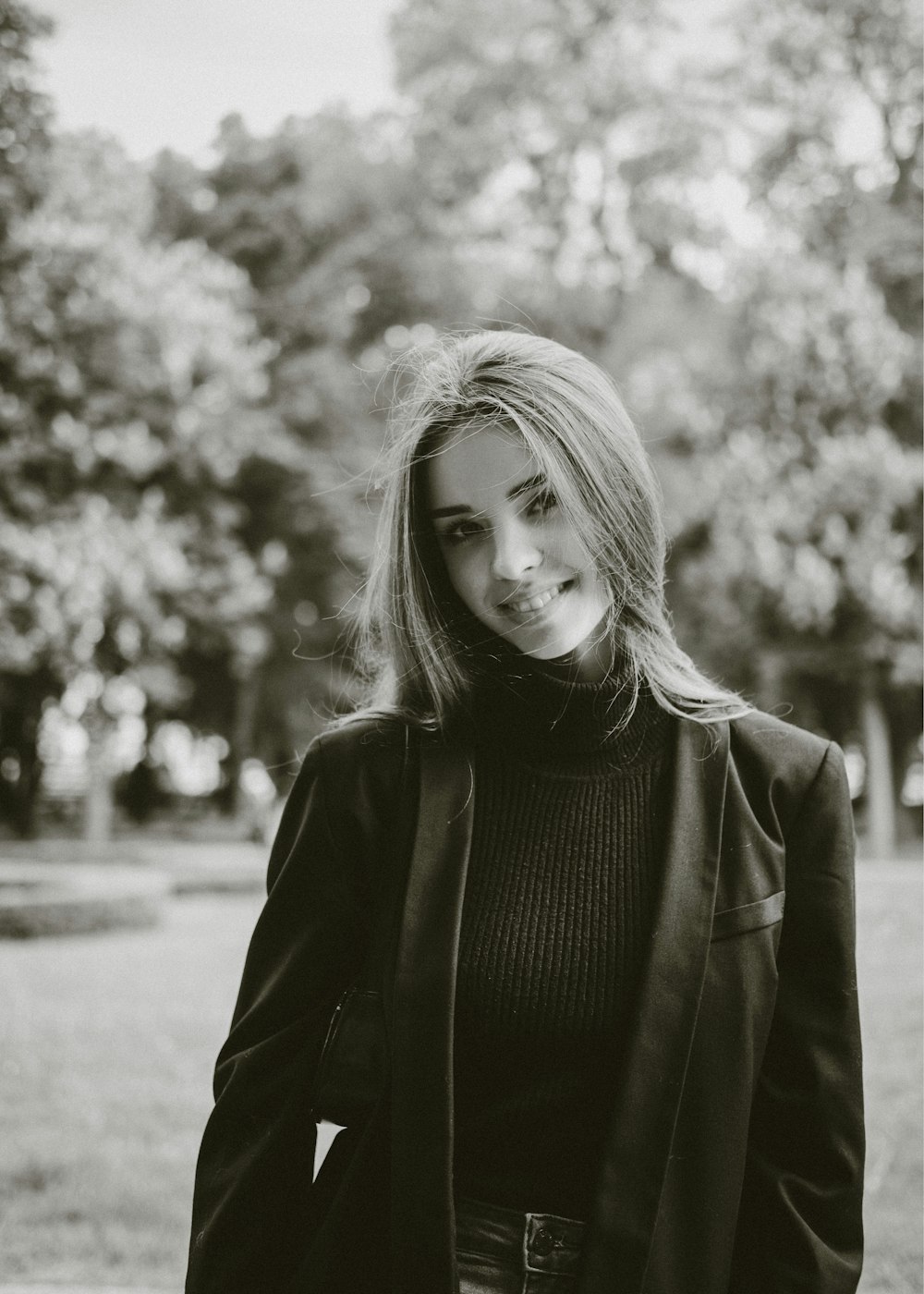 a black and white photo of a woman in a park