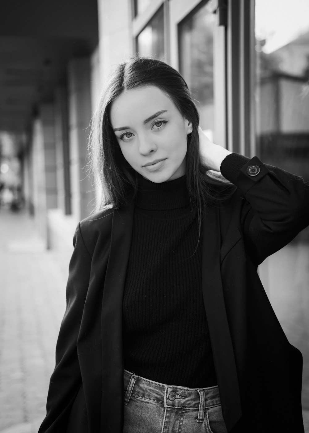 a black and white photo of a woman leaning against a building