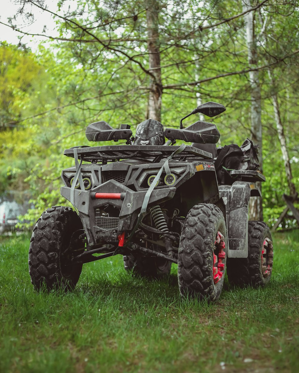 a four - wheeler is parked in the grass near a tree