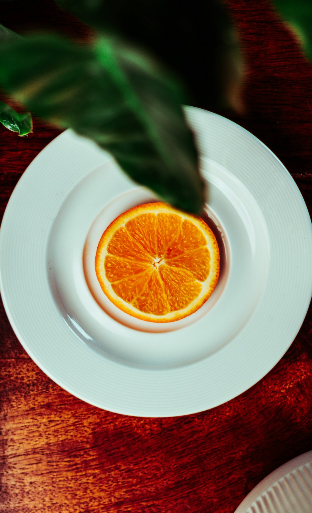 a white plate topped with an orange on top of a wooden table