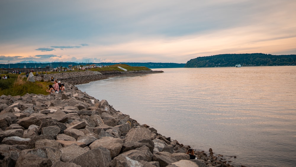 a group of people sitting on rocks near a body of water