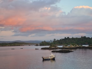 Sunset over the lush green hills of Sabana de la Mar with a small boat on calm waters