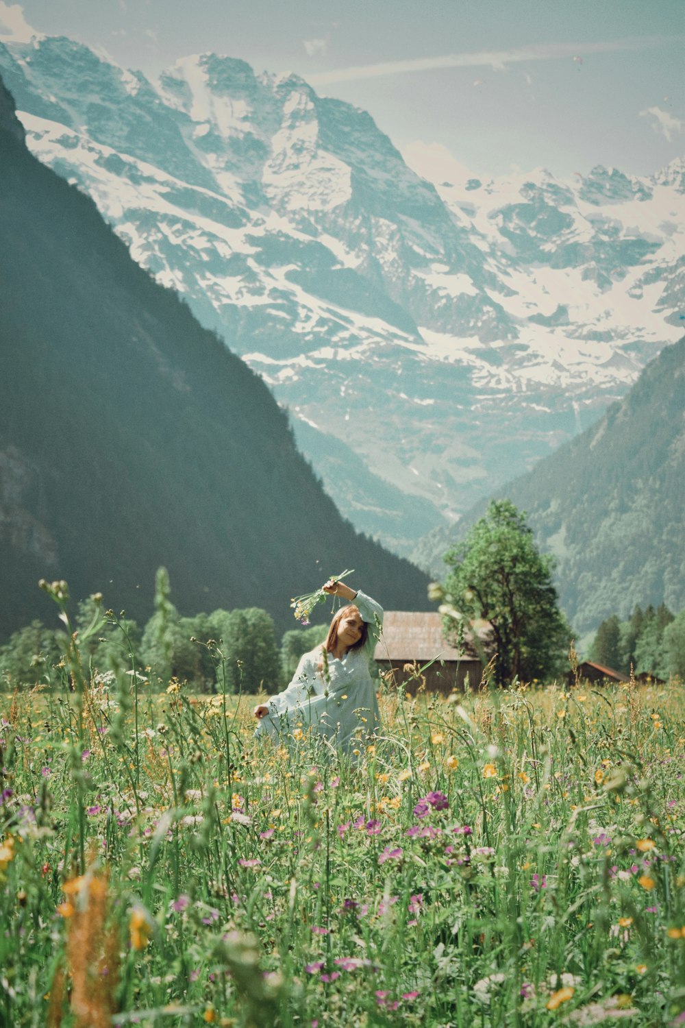 a woman standing in a field with mountains in the background