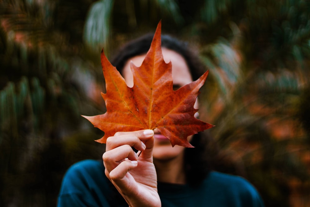 a woman holding a leaf in front of her face