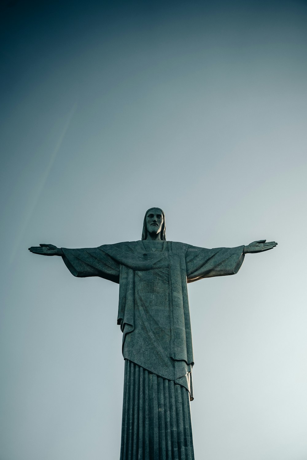a large statue of christ in the middle of a field