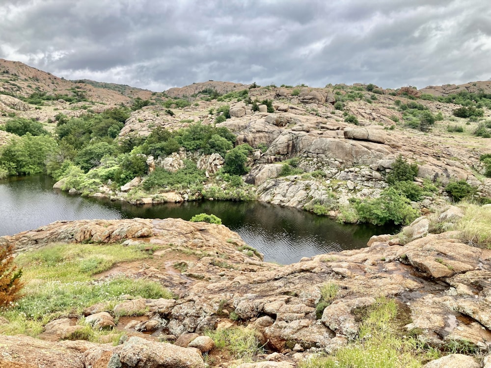 a small lake surrounded by rocks and greenery