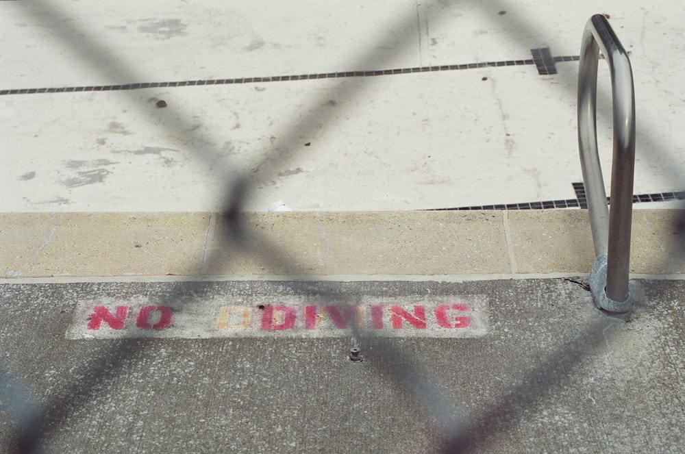 a no diving sign on a sidewalk behind a fence