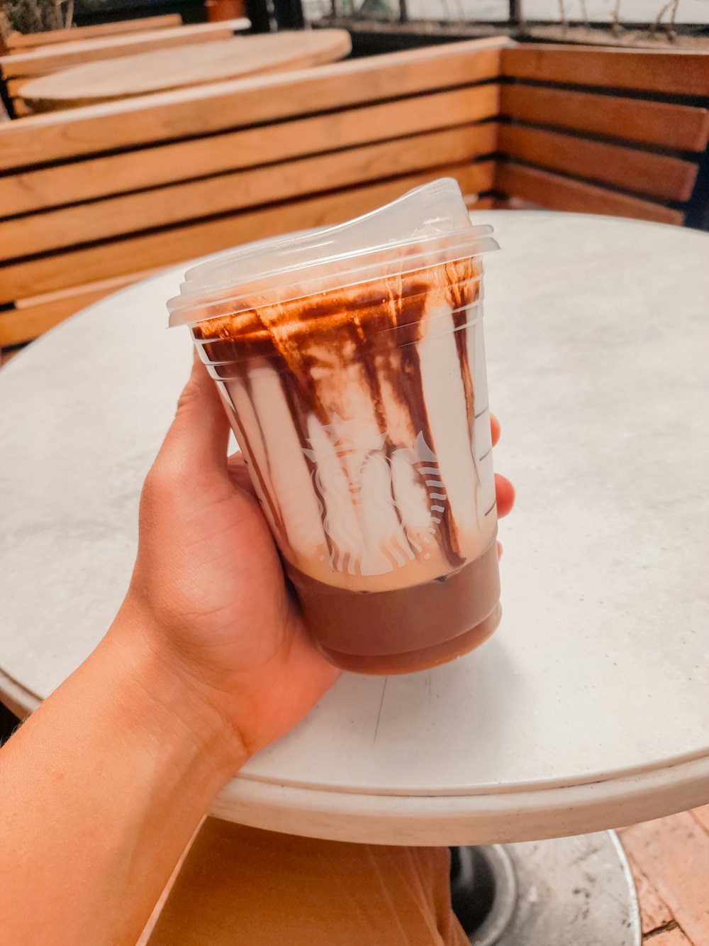 a hand holding a plastic cup filled with liquid