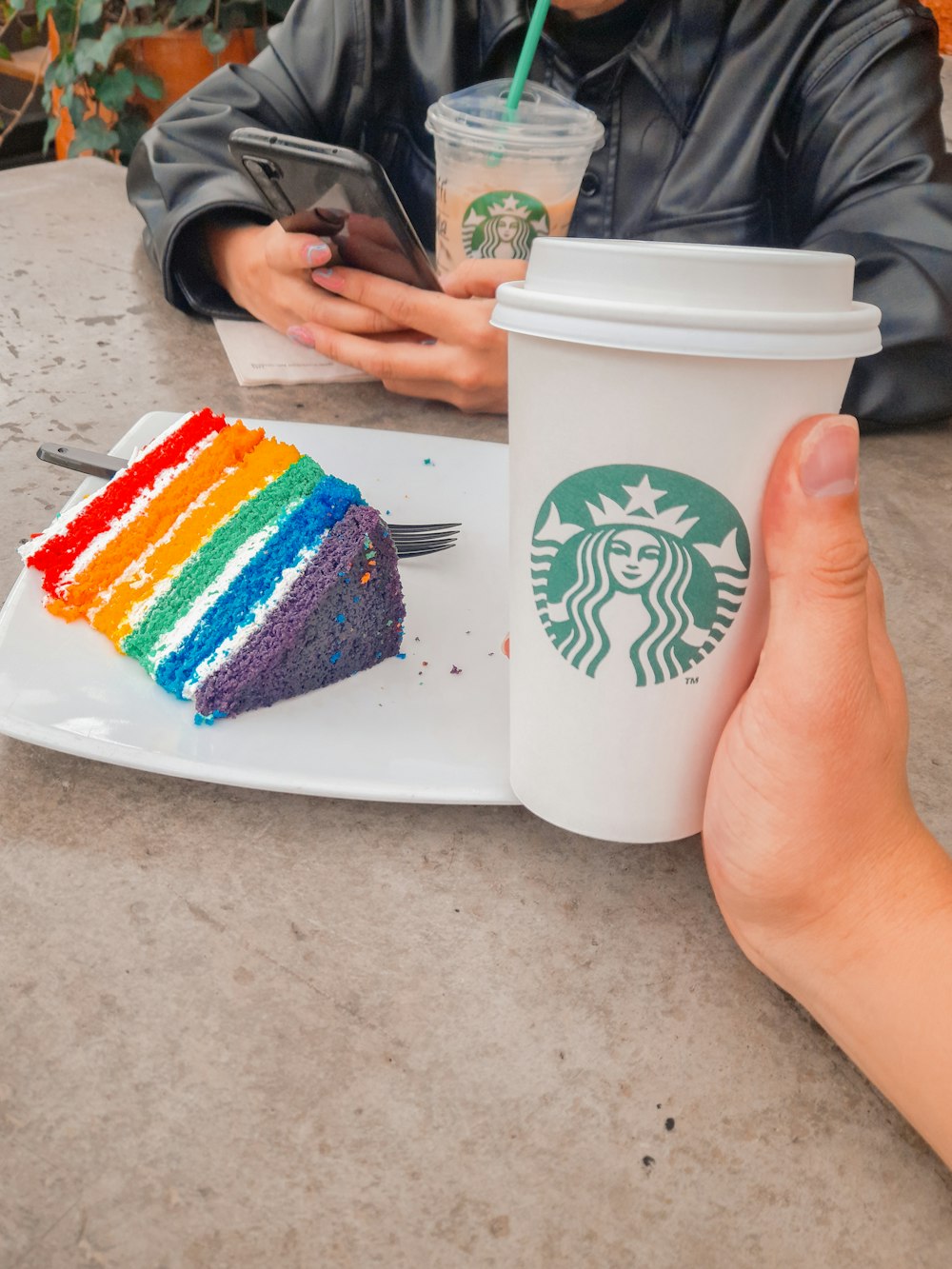 a person holding a cup of coffee and a slice of cake