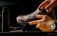 a person tying a pair of brown shoes