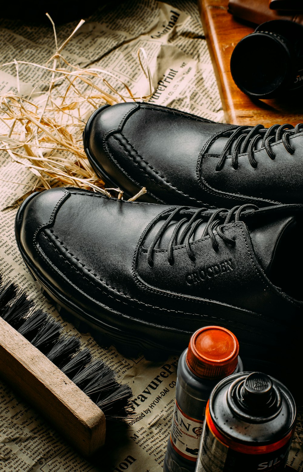 a pair of black shoes sitting on top of a newspaper