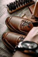 a pair of brown shoes sitting on top of a newspaper