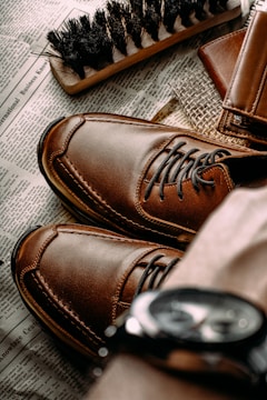 a pair of brown shoes sitting on top of a newspaper