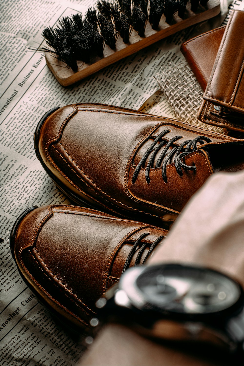 a pair of brown shoes sitting on top of a newspaper